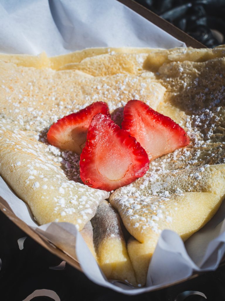 Crepe with powdered sugar and sliced strawberries on top.