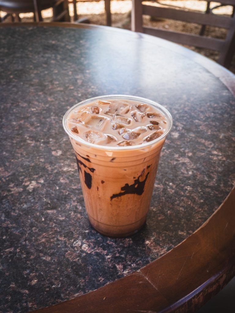 Iced coffee with milk in a plastic cup on a round table.
