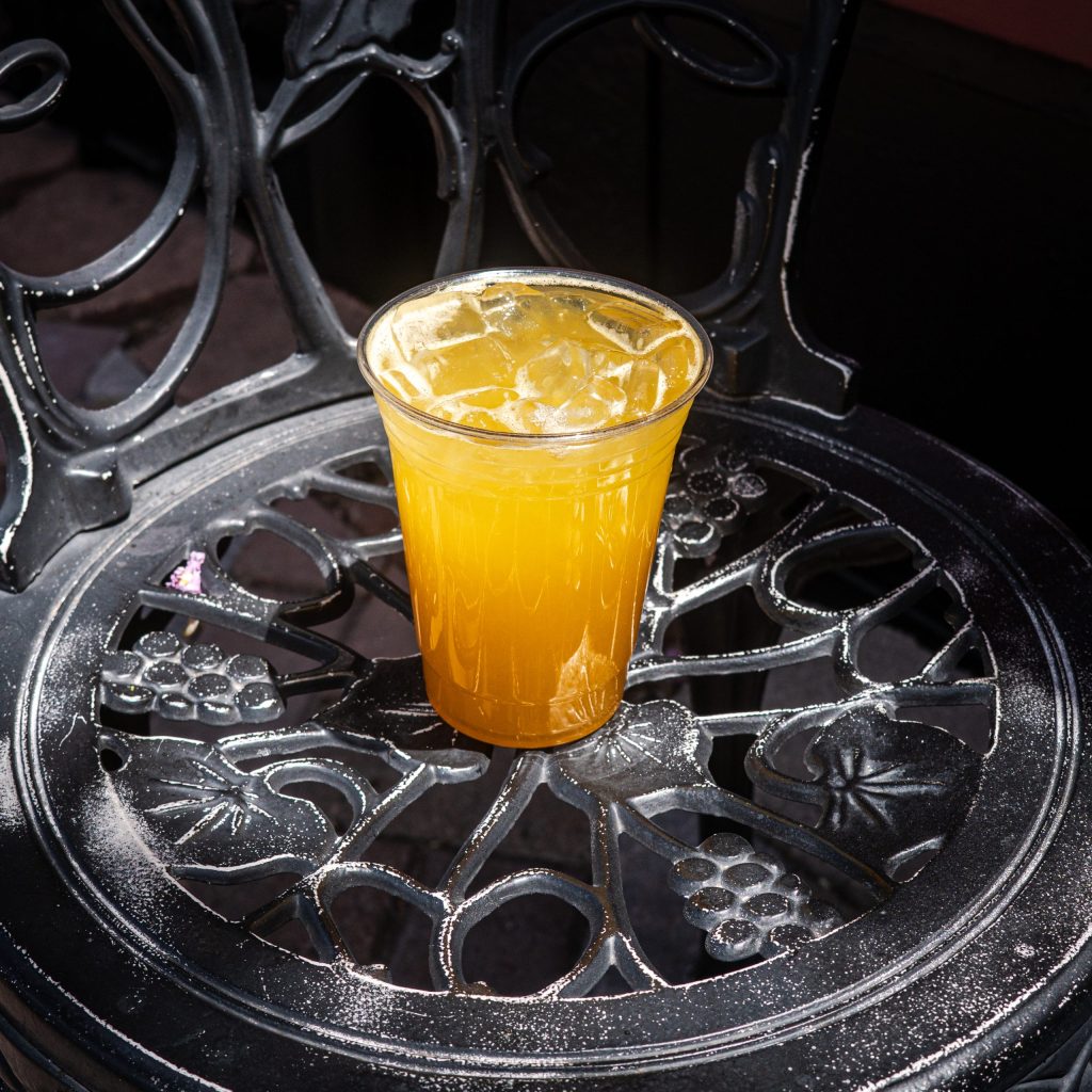 Orange drink in a plastic cup on an ornate metal chair.